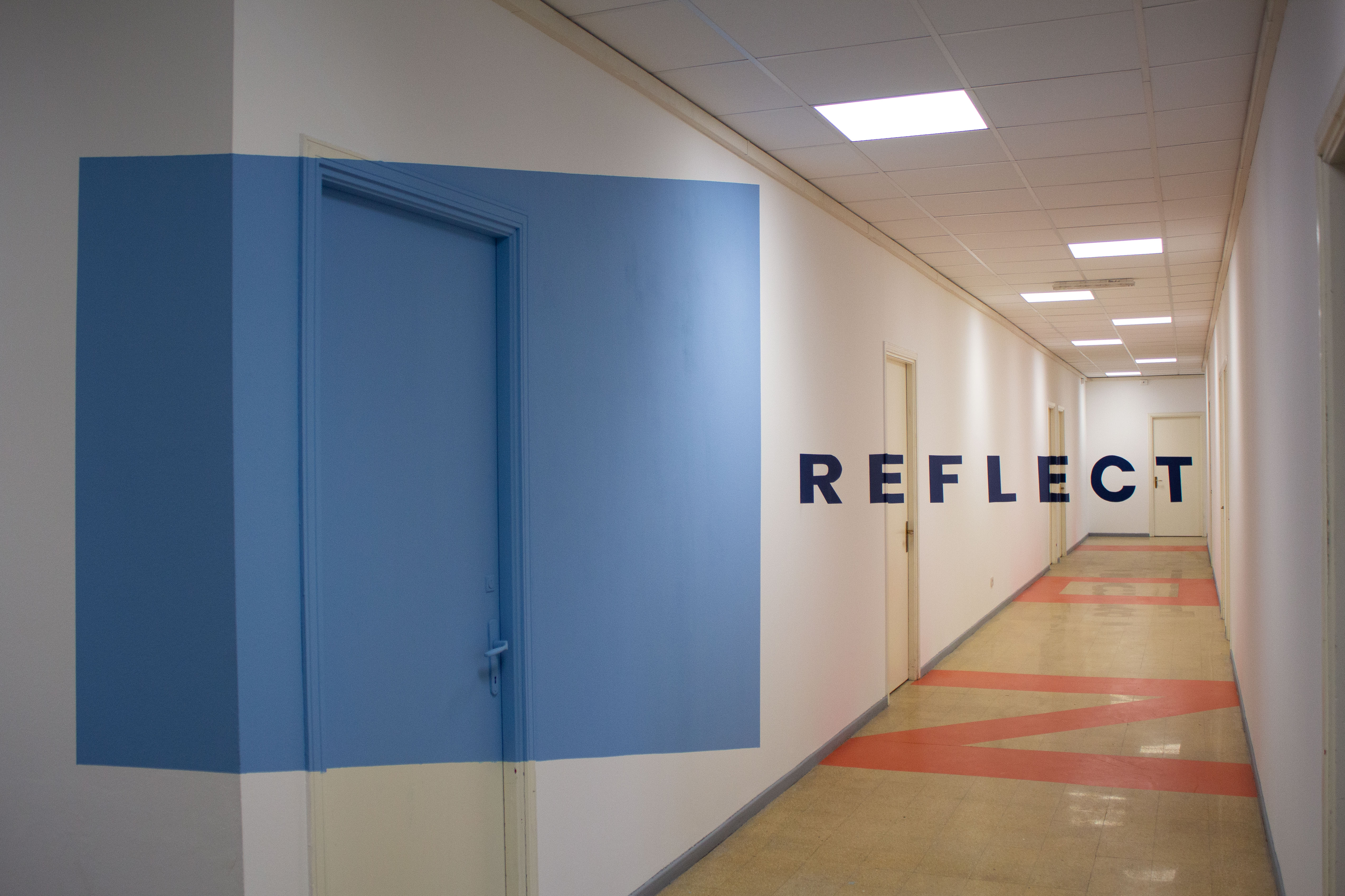 Corridoio REFLECT con porta blu, sede Torino
